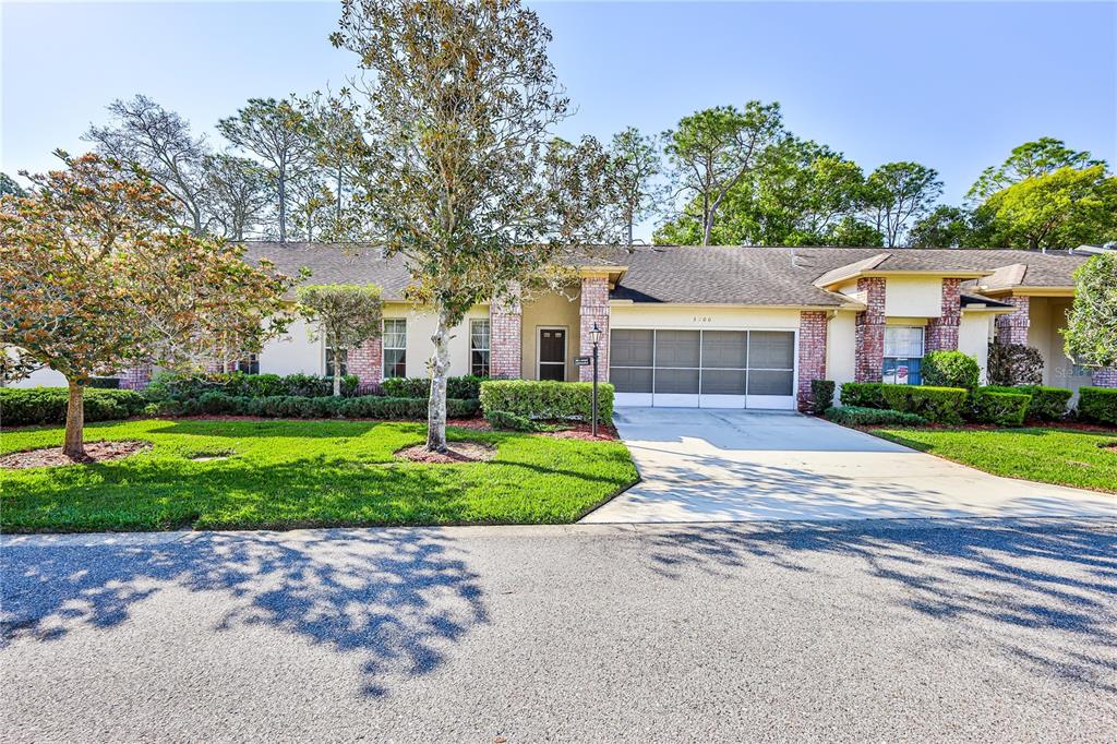 A single-story residential building with a brick facade, a concrete driveway, and a manicured lawn — 3100 APPLEBLOSSOM TRAIL, SPRING HILL, FL