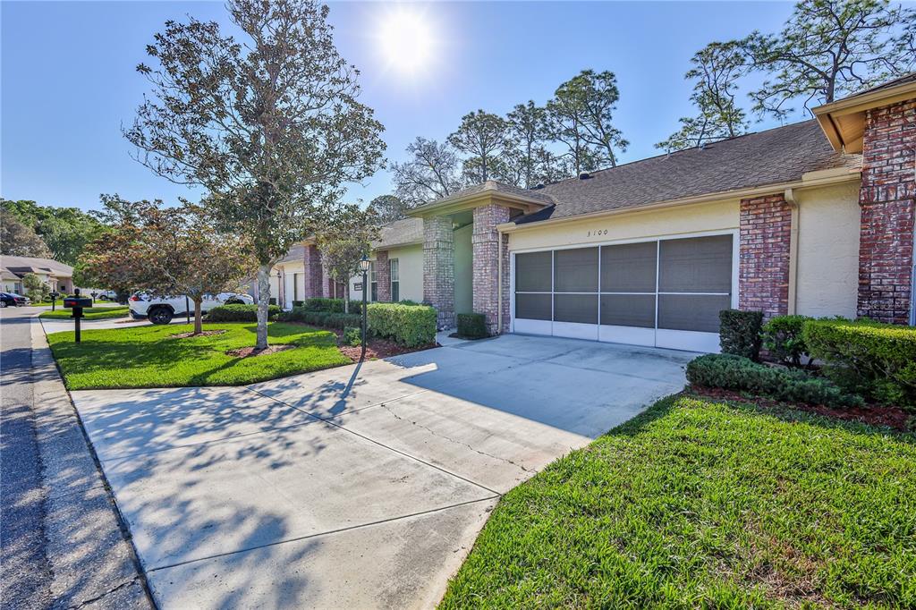 A single-story residential building features a concrete driveway, a garage, and a brick facade — 3100 APPLEBLOSSOM TRAIL, SPRING HILL, FL