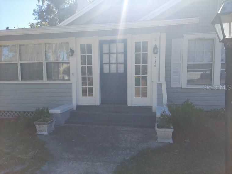 The exterior of a light blue house features a dark front door with sidelights and shutters — 616 W HOWRY AVENUE, DELAND, FL