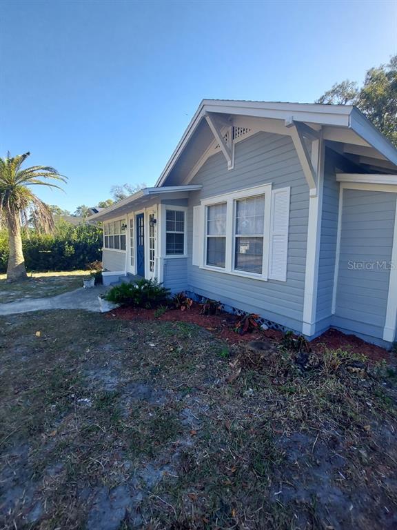 A light blue house with white trim, a gabled roof, and a palm tree nearby — 616 W HOWRY AVENUE, DELAND, FL