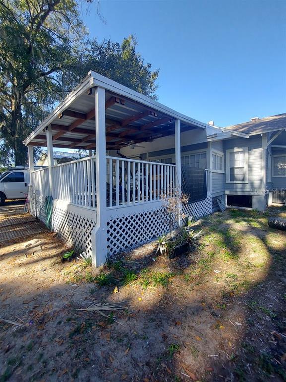 A white house features a covered wooden deck with lattice skirting and a metal roof — 616 W HOWRY AVENUE, DELAND, FL
