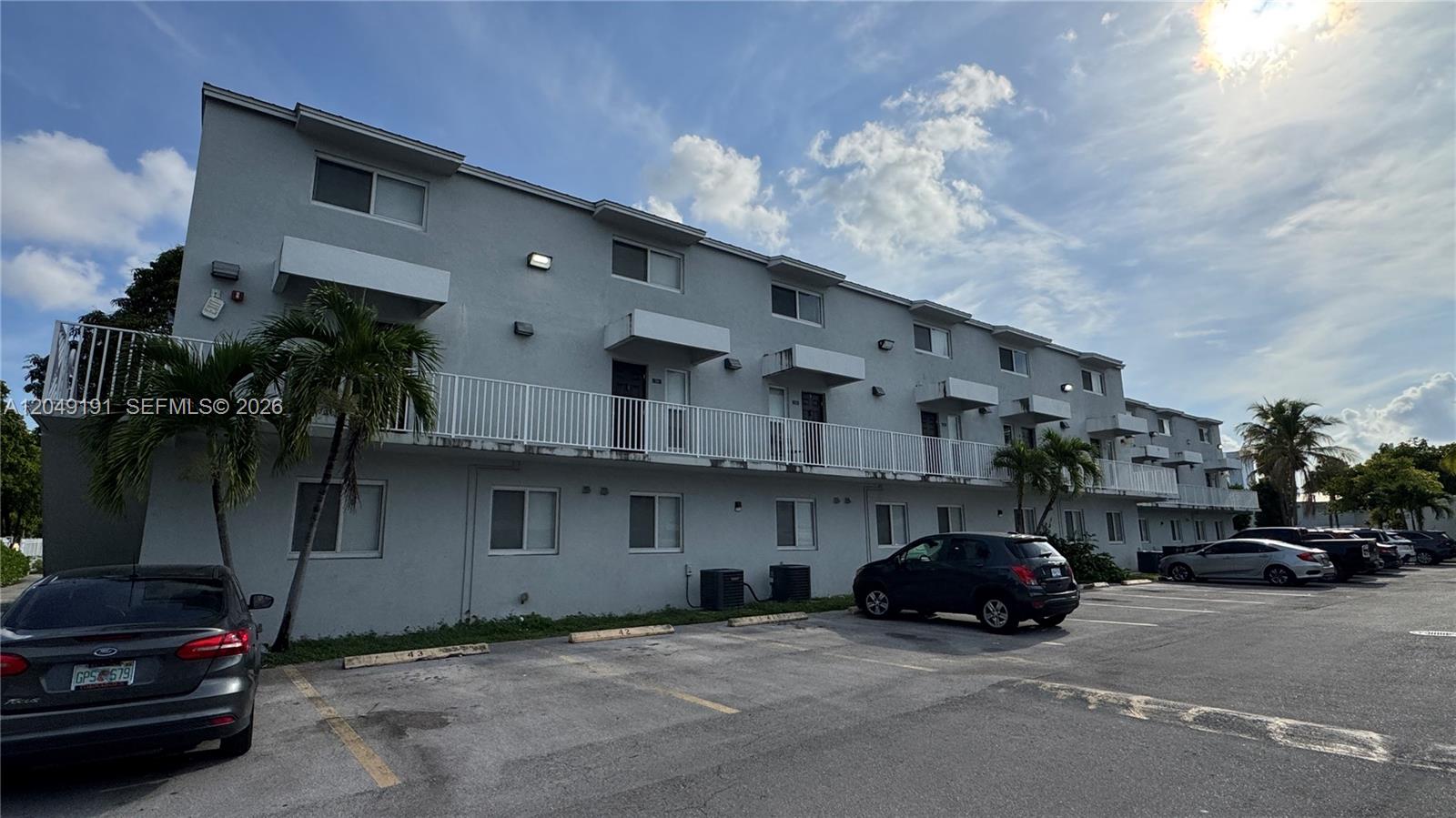 A three-story apartment building with a white balcony and a parking lot in front — 1955 NW 5th Pl # 11, Miami FL 33136, MIAMI, FL