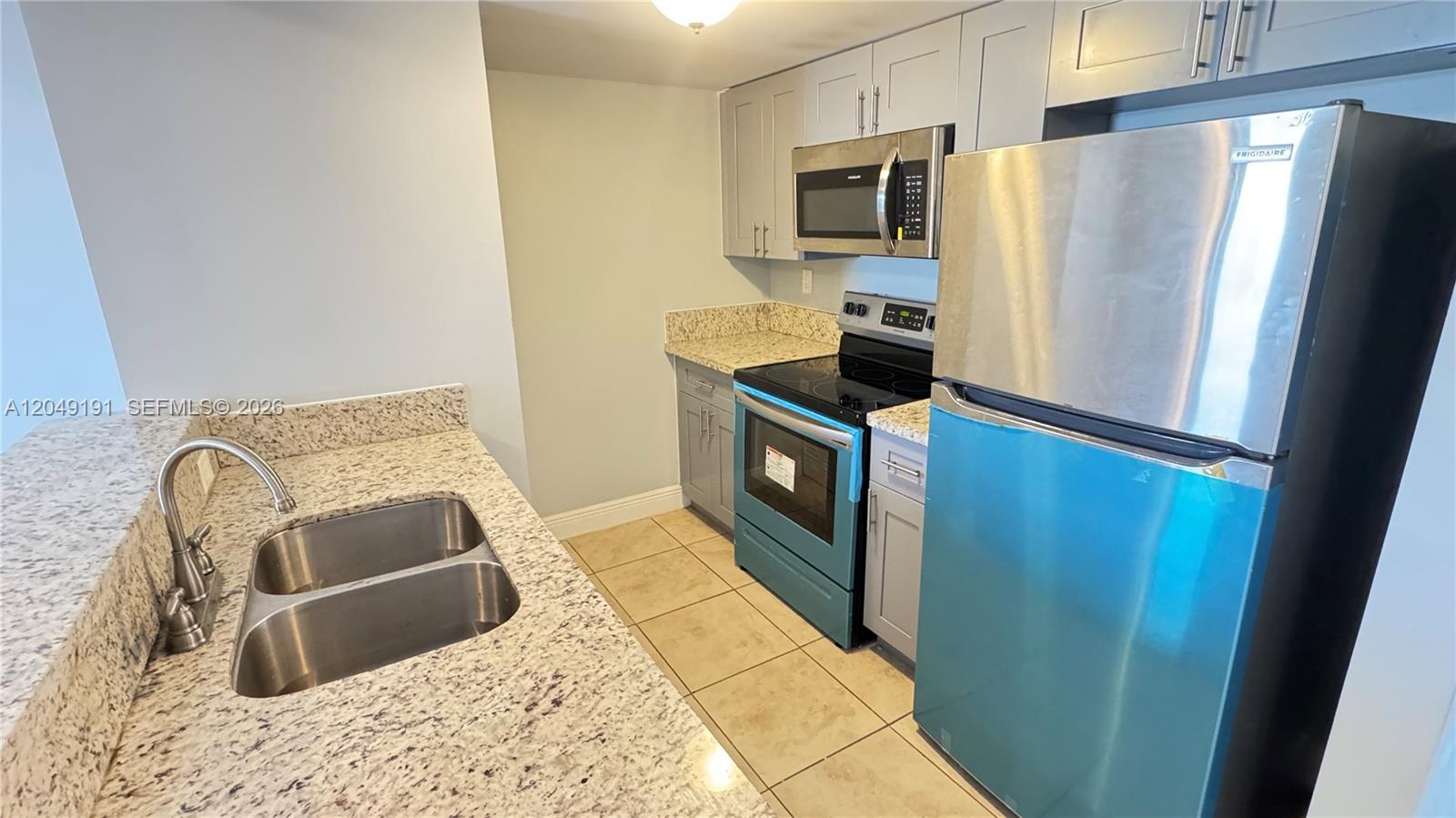 A kitchen features gray cabinets, granite countertops, stainless steel appliances, and a double-basin sink — 1955 NW 5th Pl # 11, Miami FL 33136, MIAMI, FL