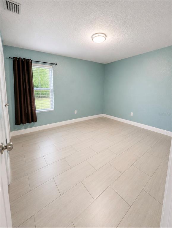 An empty bedroom features light blue walls, light-colored tile flooring, and a single window — 401 MORNINGSIDE, VALRICO, FL