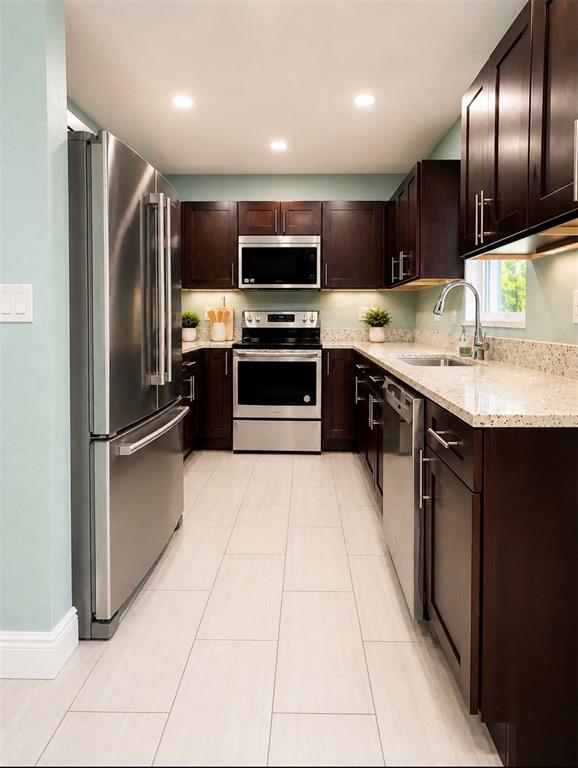 A galley kitchen features dark wood cabinets, stainless steel appliances, and light-colored granite countertops — 401 MORNINGSIDE, VALRICO, FL