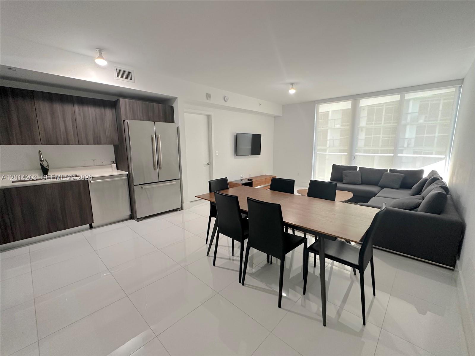 A modern open-concept living and dining area features white tile floors and dark wood cabinetry — 488 NE 18th St # 2502, Miami FL 33132, MIAMI, FL