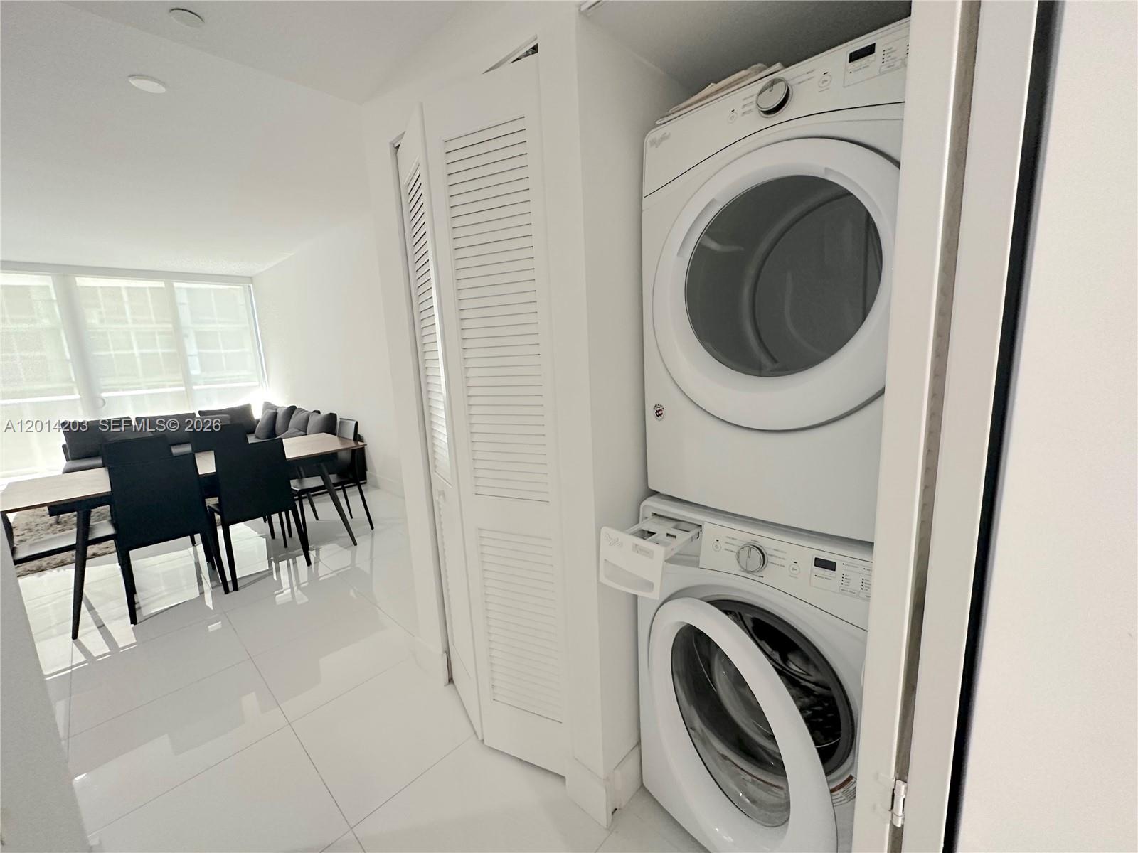 A stacked washer and dryer unit is located in a closet next to a dining area — 488 NE 18th St # 2502, Miami FL 33132, MIAMI, FL