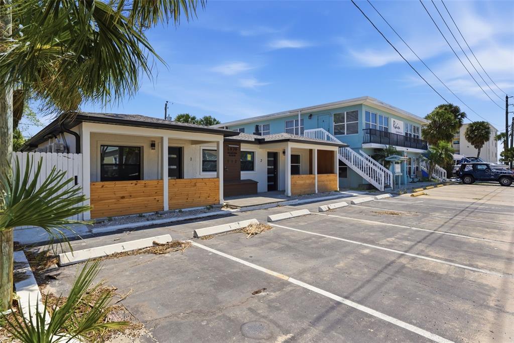 An exterior view of a single-story building with wood-paneled porches and an adjacent parking lot — 113 145TH AVENUE E UNIT 1, MADEIRA BEACH, FL