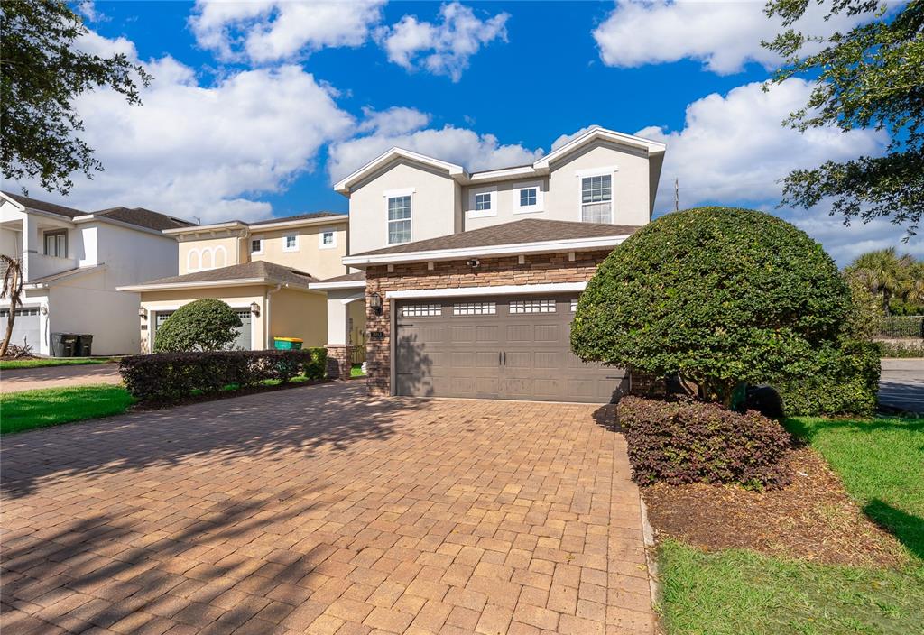 A two-story house with a stone-accented garage and a paved driveway under a blue sky — 380 PENDANT COURT, KISSIMMEE, FL