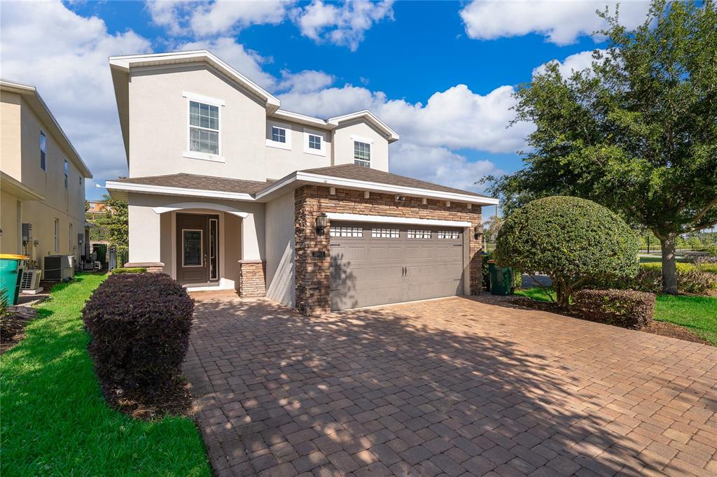 A two-story house with a stone-accented garage and a paved driveway under a blue sky — 380 PENDANT COURT, KISSIMMEE, FL