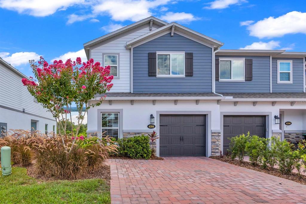 A two-story townhouse with blue siding, a brick driveway, and a single-car garage — 4394 CAMPSITE LOOP, ORLANDO, FL