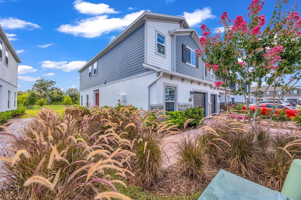 A two-story townhouse with blue and white siding, a stone facade, and landscaped front yard — 4394 CAMPSITE LOOP, ORLANDO, FL