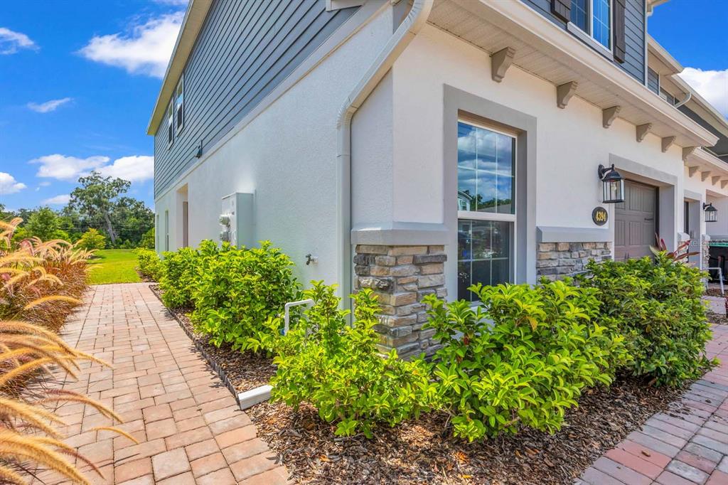 A side view of a two-story house with stone accents, a brick walkway, and landscaping — 4394 CAMPSITE LOOP, ORLANDO, FL