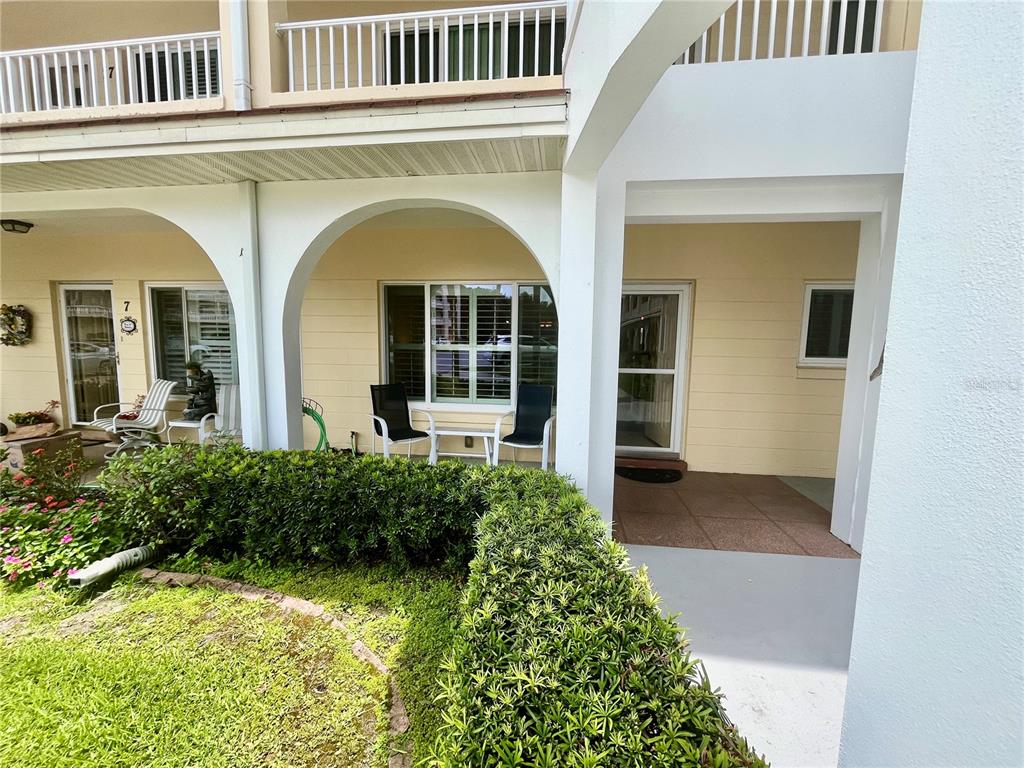 A ground-level patio area features arched openings, outdoor seating, and a manicured hedge — 2223 PHILIPPINE DRIVE UNIT 9, CLEARWATER, FL