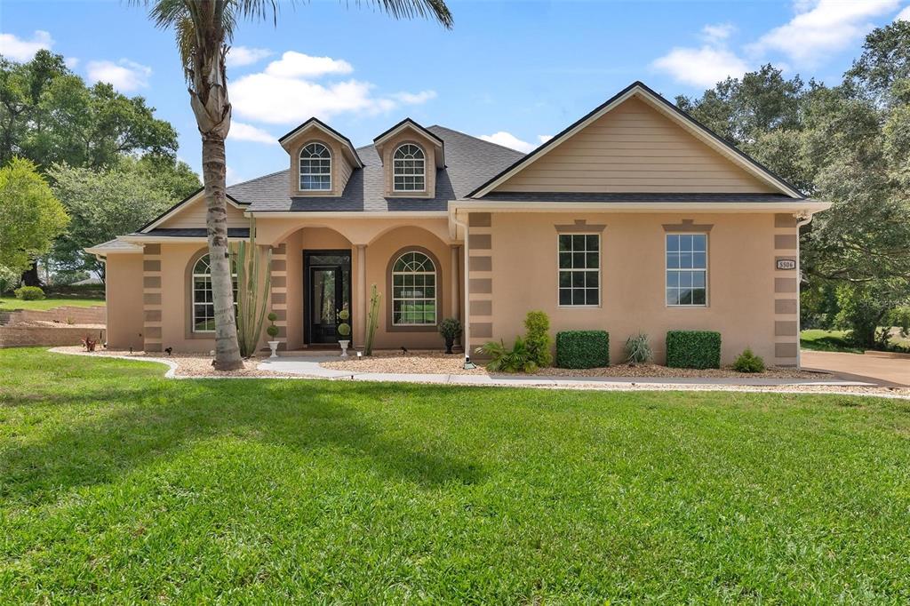 A tan, single-story house with a palm tree, two dormer windows, and a front entrance — 5506 CITATION COURT, LADY LAKE, FL