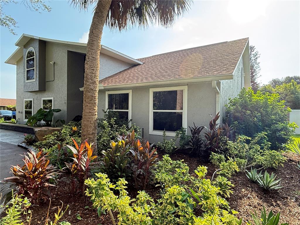 A gray two-story house features a palm tree and landscaping in the front yard — 1 HARRIS CIRCLE, EDGEWATER, FL