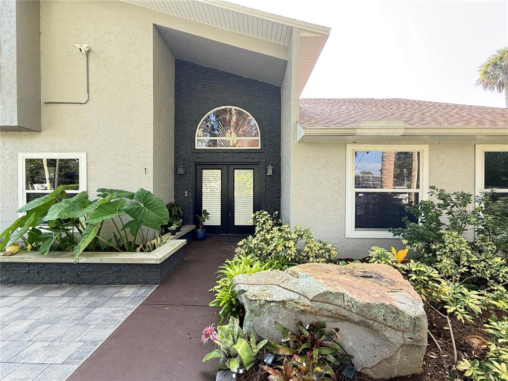 The exterior of a house features a dark stone entryway with double doors and landscaping — 1 HARRIS CIRCLE, EDGEWATER, FL