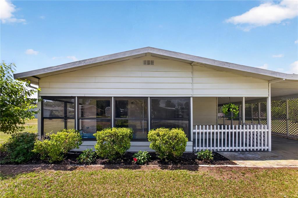 A single-story house exterior features a screened-in porch, white siding, and a white picket fence — 8972 SW 103RD LANE, OCALA, FL