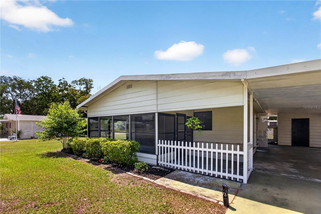 A single-story home features a screened-in porch, a white picket fence, and an attached carport — 8972 SW 103RD LANE, OCALA, FL