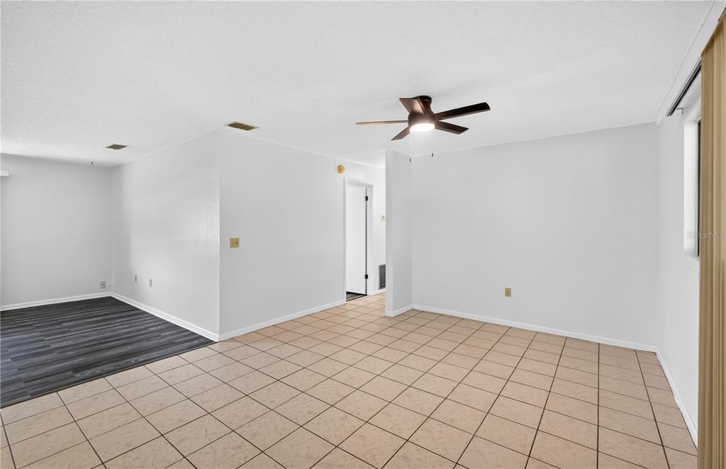An interior view of a room featuring light-colored floor tiles and a ceiling fan — 8972 SW 103RD LANE, OCALA, FL
