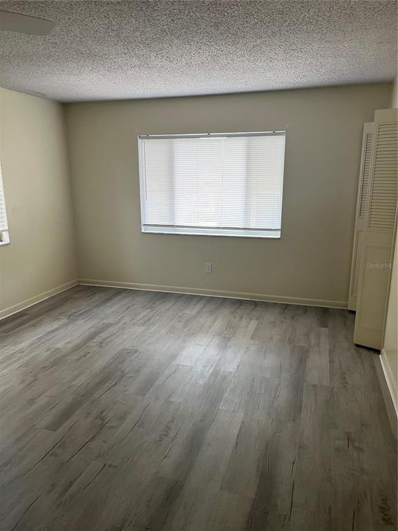 An empty bedroom features light gray wood-look flooring, beige walls, and a window with blinds — 234 KRIDER ROAD, SANFORD, FL