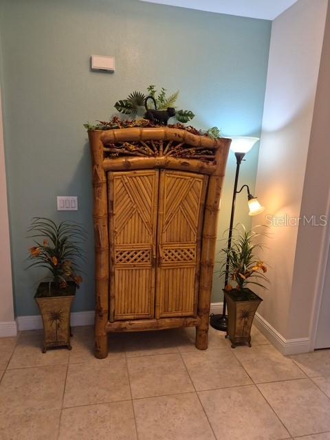A bamboo cabinet stands between two potted plants against a light blue wall — 11940 TAPESTRY LANE, VENICE, FL