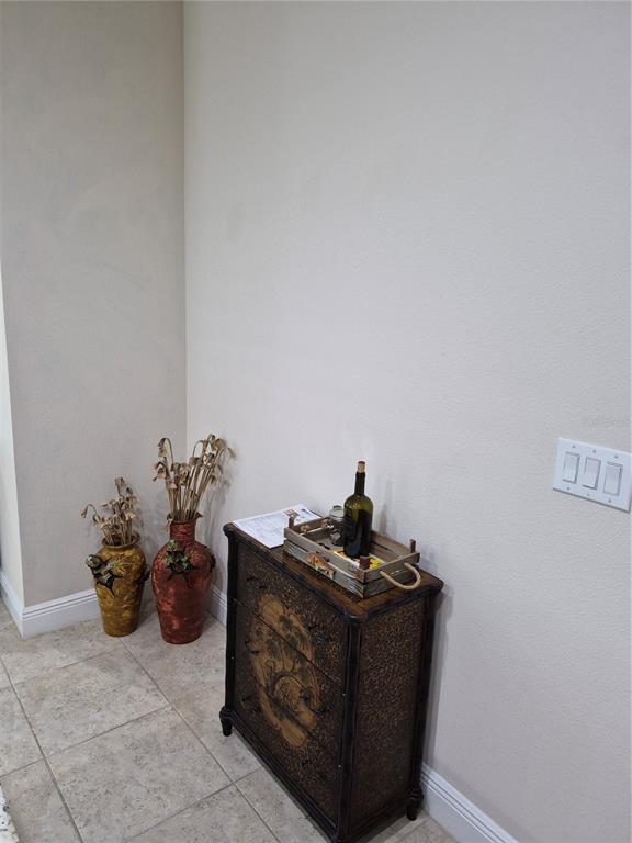 A small wooden cabinet sits in a corner next to two decorative floor vases — 11940 TAPESTRY LANE, VENICE, FL