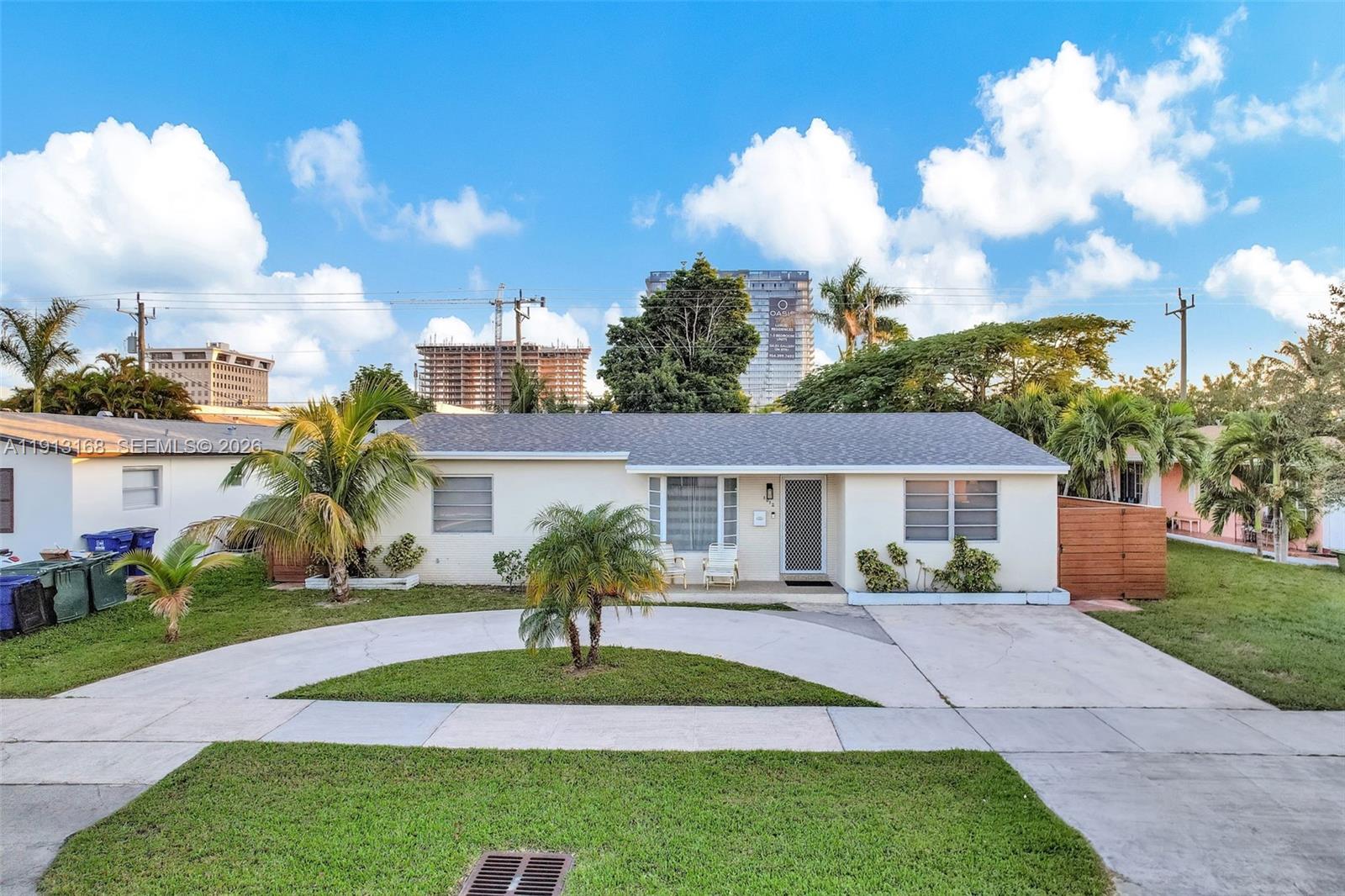 A single-story house with a circular driveway, palm trees, and a gray shingled roof — 1012 NE 2nd Street, Hallandale Beach FL 33009, HALLANDALE BEACH, FL