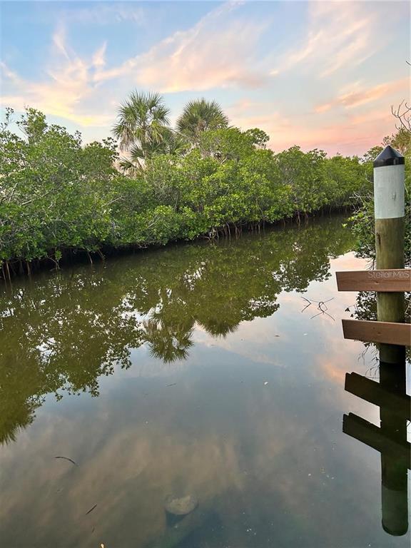 A wooden piling stands in a calm canal lined with mangroves under a sunset sky — 16907 ACAPULCO ROAD, PUNTA GORDA, FL