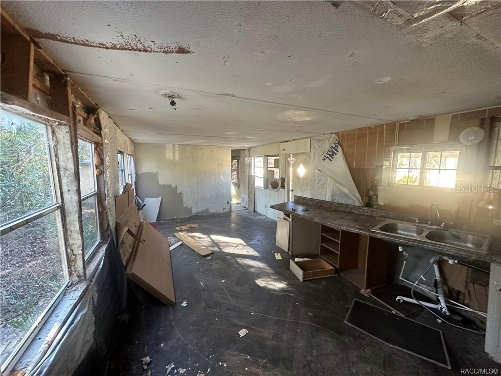 An unfinished room with exposed wall studs, a kitchen sink, and bare subflooring — 8832 E FREEMAN COURT, FLORAL CITY, FL