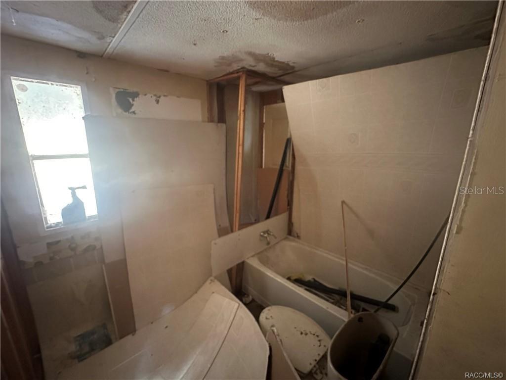 A bathroom in disrepair with exposed wall framing, a bathtub, and a toilet — 8832 E FREEMAN COURT, FLORAL CITY, FL