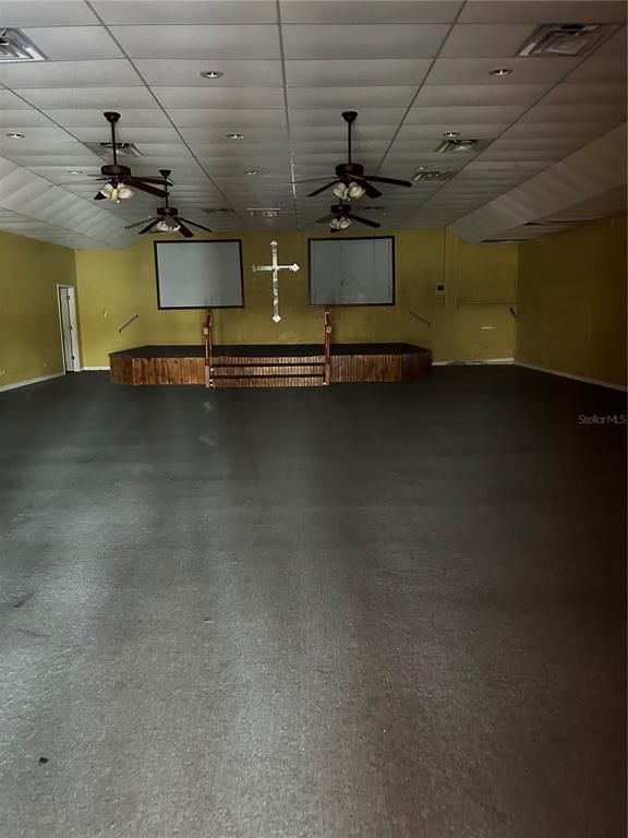 An interior view of a large room with a stage, a cross, and ceiling fans — 5819 N 56TH STREET UNIT 1, TAMPA, FL