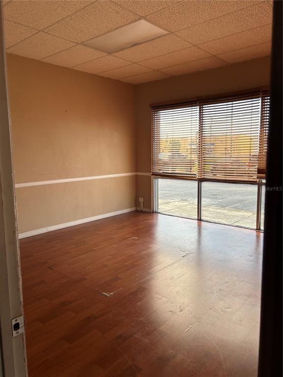 An empty office room features wood-look flooring, beige walls with chair rail molding, and window blinds — 5819 N 56TH STREET UNIT 1, TAMPA, FL