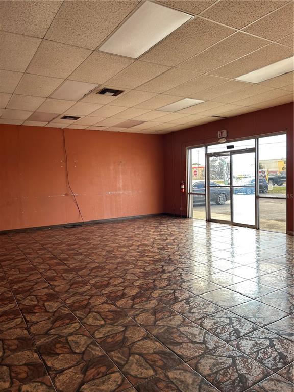 An empty commercial space features orange walls, a drop ceiling, and patterned tile flooring — 5819 N 56TH STREET UNIT 1, TAMPA, FL