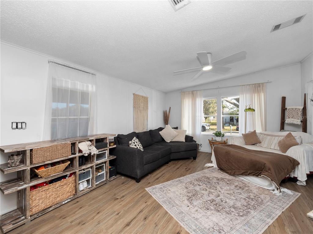 A living room features wood-look flooring, a dark sectional sofa, and a wooden storage unit — 216 ELLSWORTH DRIVE, KISSIMMEE, FL