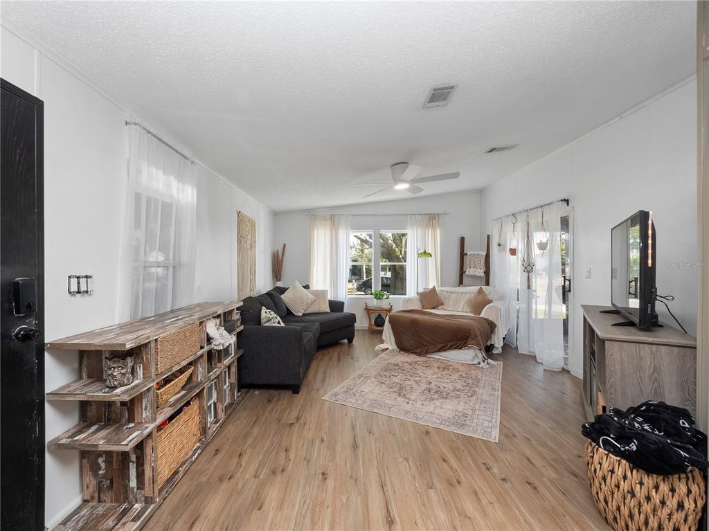 A living room features light wood flooring, white walls, a dark sectional, and a television console — 216 ELLSWORTH DRIVE, KISSIMMEE, FL