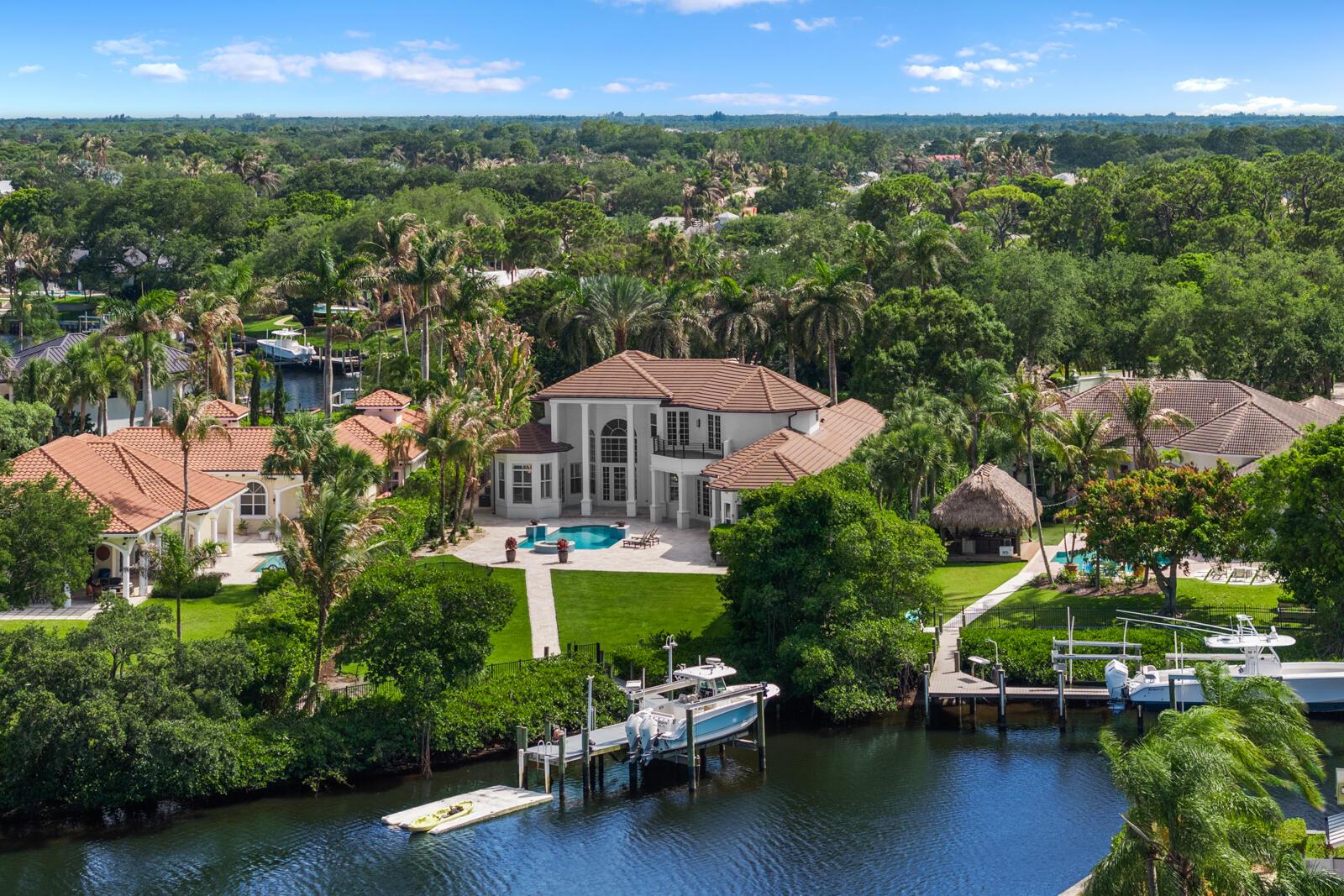 An aerial view of a waterfront house with a pool, dock, and two boats — 8709 SE Compass Island Way, Jupiter FL 33458, JUPITER, FL