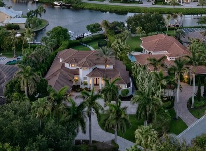 An aerial view shows a large white house with a brown tile roof and palm trees — 8709 SE Compass Island Way, Jupiter FL 33458, JUPITER, FL