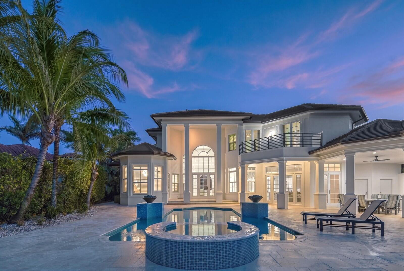 A two-story house with a pool, hot tub, and palm trees at dusk — 8709 SE Compass Island Way, Jupiter FL 33458, JUPITER, FL