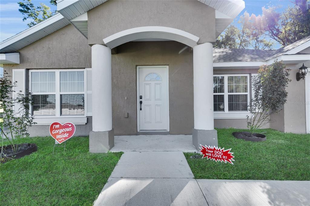 The front exterior of a single-story house features a white door, columns, and two signs — 1645 SW 168TH LOOP, OCALA, FL