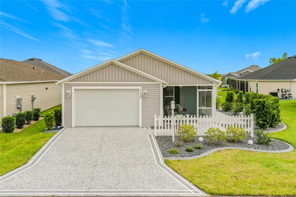 A single-story house with light gray siding, a two-car garage, and a white picket fence — 1758 YVONIA COURT, THE VILLAGES, FL
