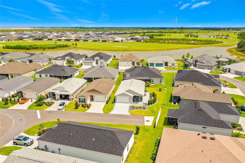 An aerial view shows a suburban neighborhood with houses, lawns, and a nearby golf course — 1758 YVONIA COURT, THE VILLAGES, FL