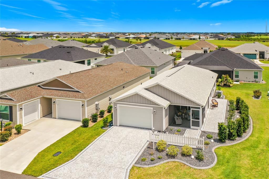 An aerial view shows two adjacent suburban houses with driveways, garages, and landscaped yards — 1758 YVONIA COURT, THE VILLAGES, FL