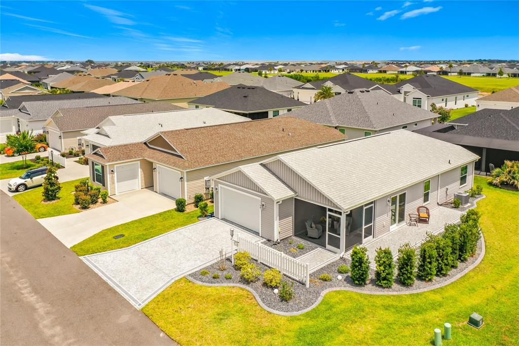 An aerial view shows a suburban neighborhood with single-story houses, driveways, and landscaped yards — 1758 YVONIA COURT, THE VILLAGES, FL