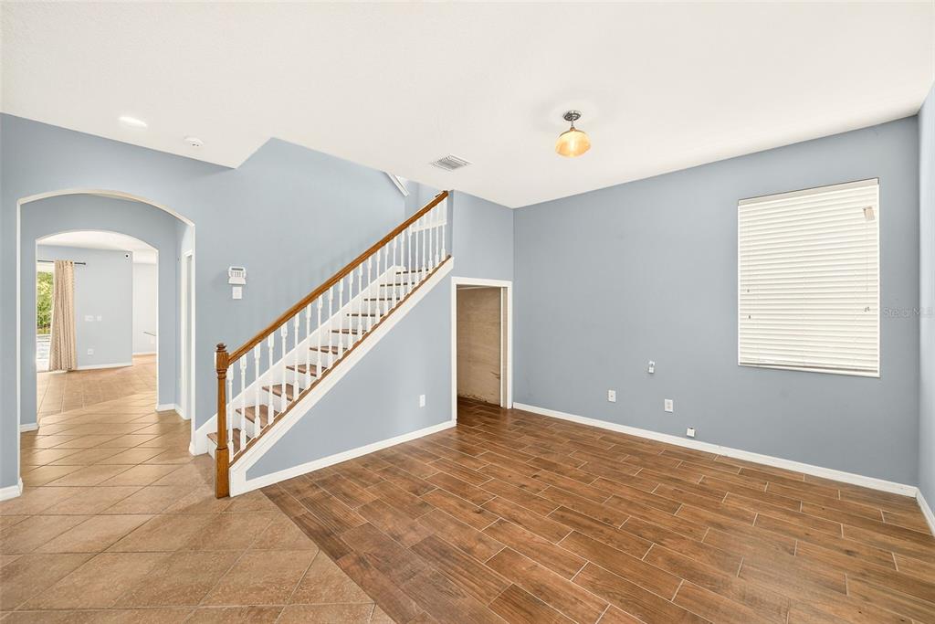 An empty room features light blue walls, wood-look tile flooring, and a staircase with white railings — 2917 WINGLEWOOD CIRCLE, LUTZ, FL