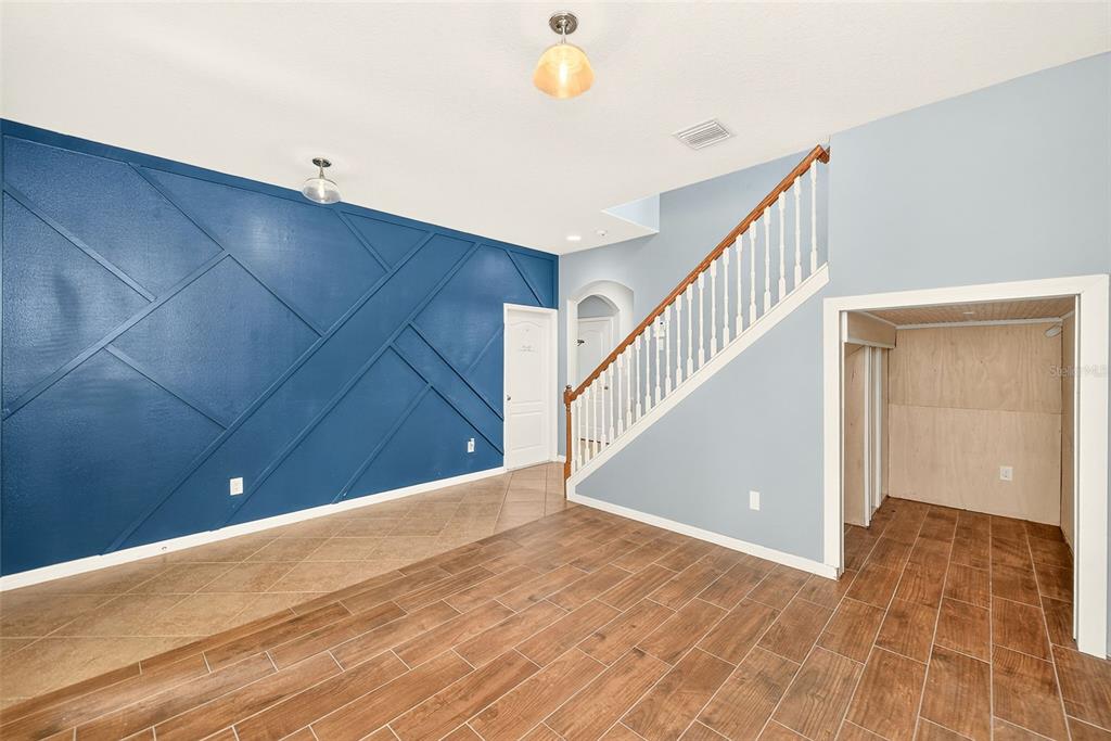 An interior view shows a room with wood-look tile flooring, a blue accent wall, and stairs — 2917 WINGLEWOOD CIRCLE, LUTZ, FL