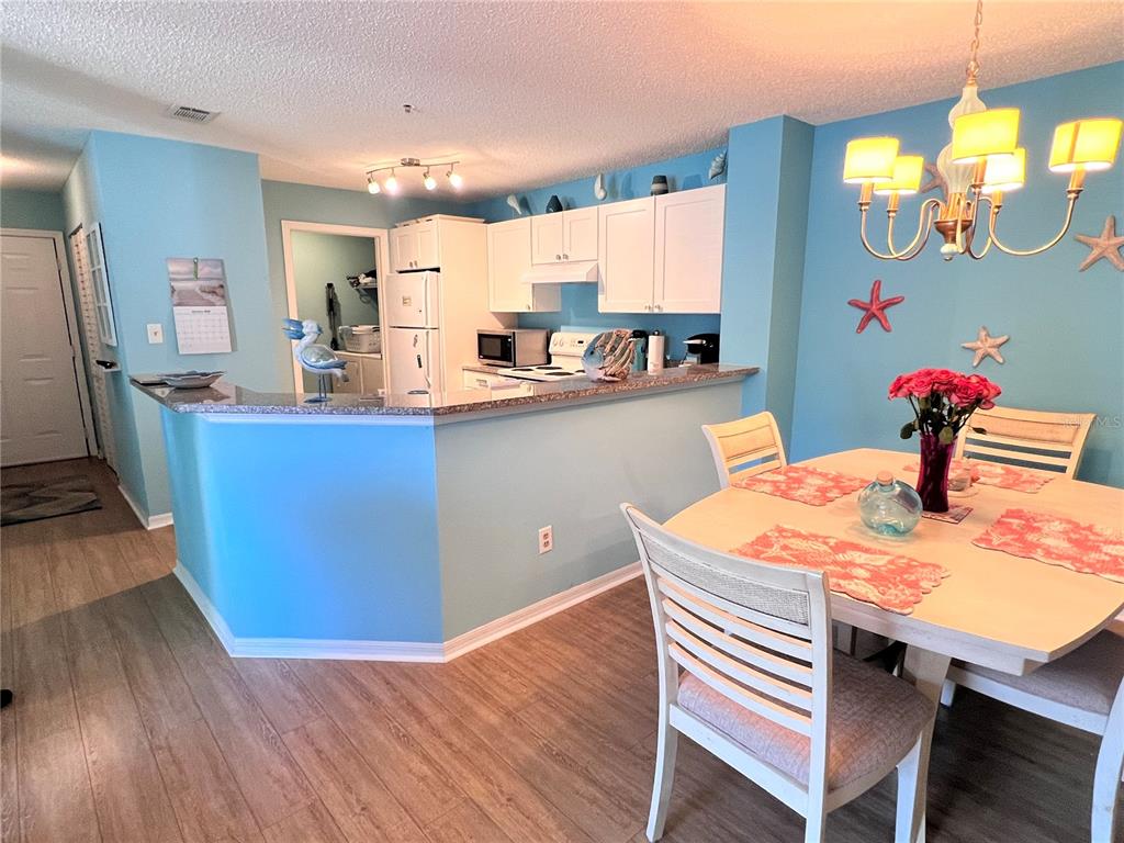 A kitchen with white cabinets and a breakfast bar opens into a dining area — 4040 CROCKERS LAKE BOULEVARD UNIT 1717, SARASOTA, FL