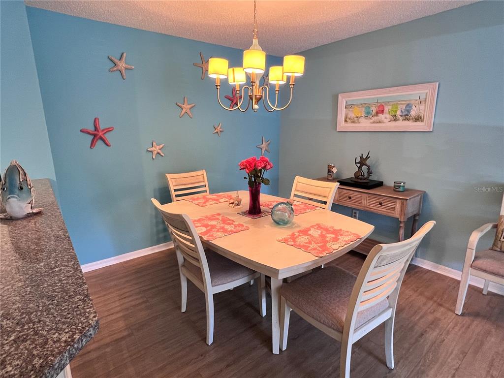 A dining room features a light-colored table, four chairs, and blue walls with starfish decor — 4040 CROCKERS LAKE BOULEVARD UNIT 1717, SARASOTA, FL