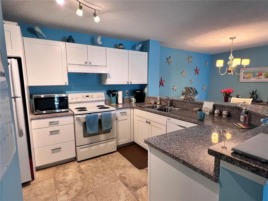 A kitchen with white cabinets, blue walls, a speckled countertop, and a tile floor — 4040 CROCKERS LAKE BOULEVARD UNIT 1717, SARASOTA, FL