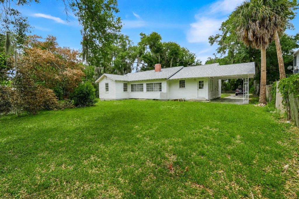 A white, single-story house with a carport and a large, grassy backyard — 504 E CITRUS AVE, EUSTIS, FL